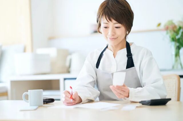 自宅のテーブルで家計簿をつけている様子